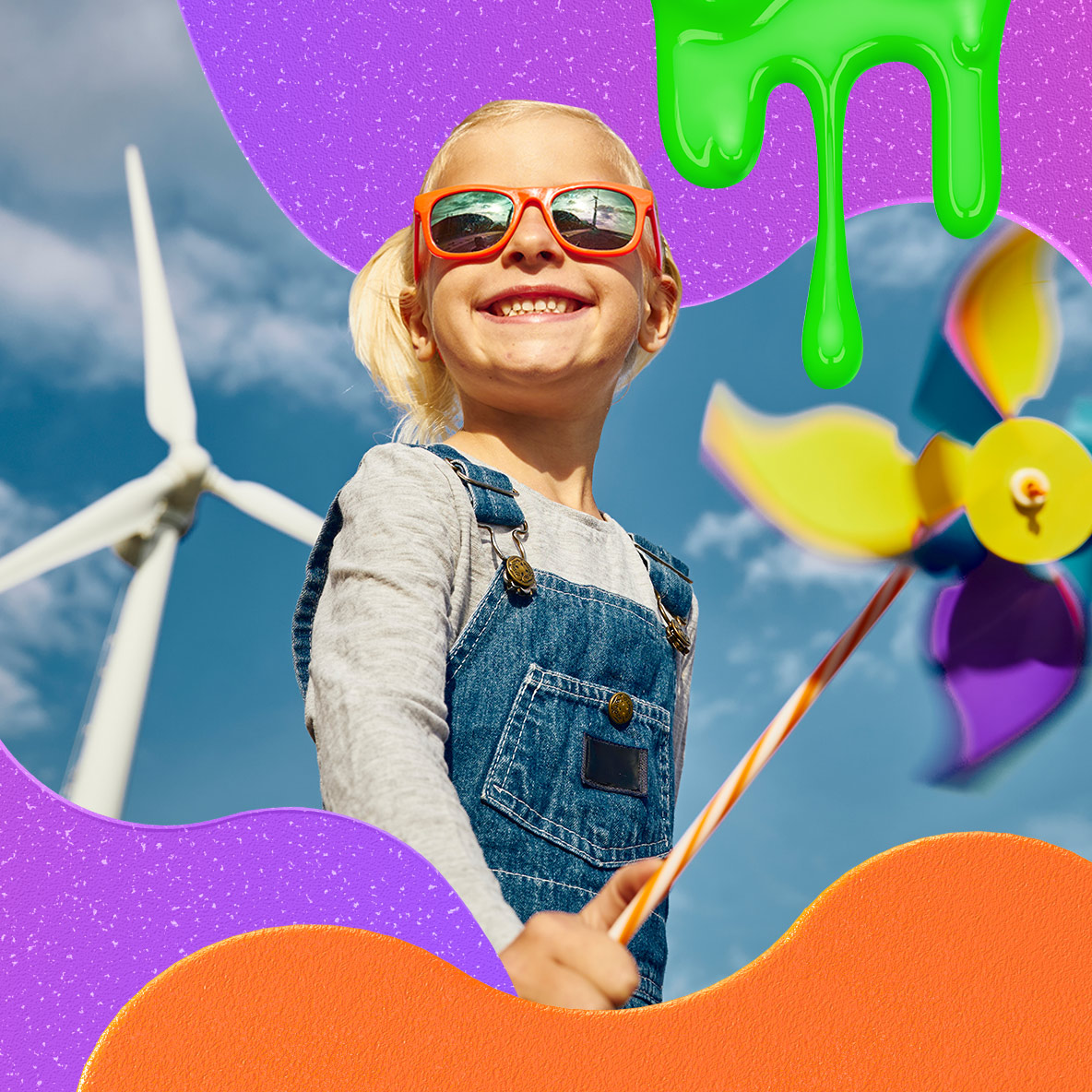 A young white girl with a blond ponytail poses in front of a windmill smiling, holding a toy pinwheel.